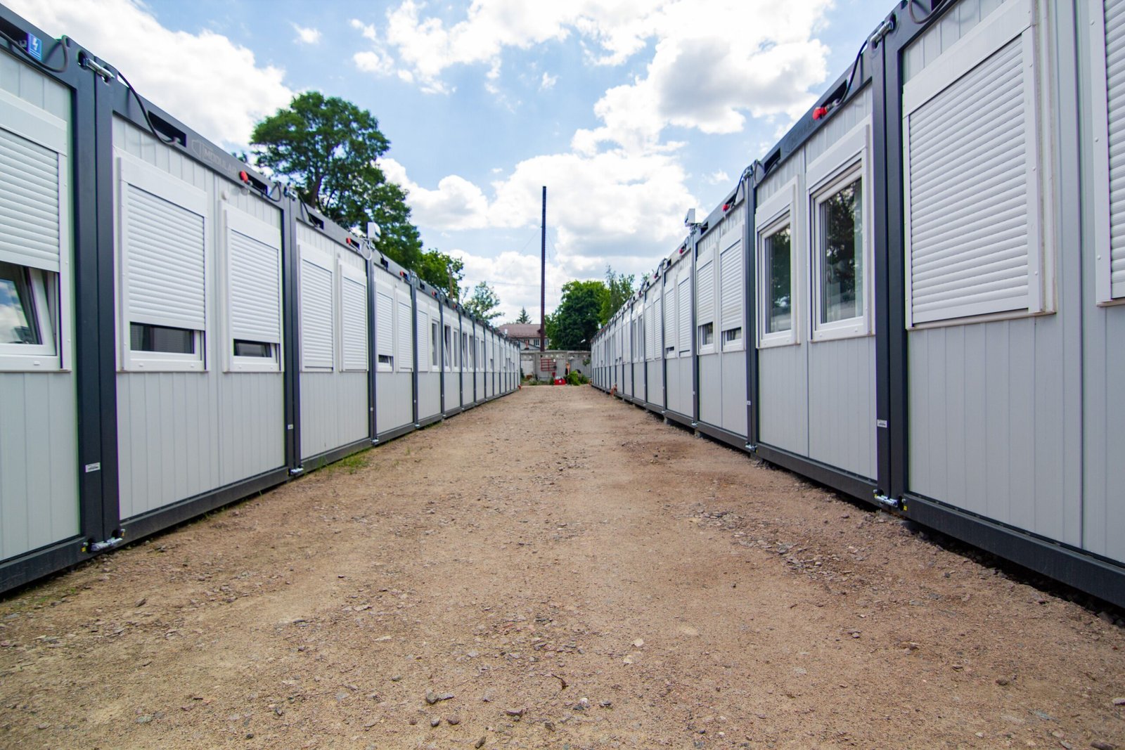 A clear sky view of two rows of temporary office buildings with a dirt pathway in between.