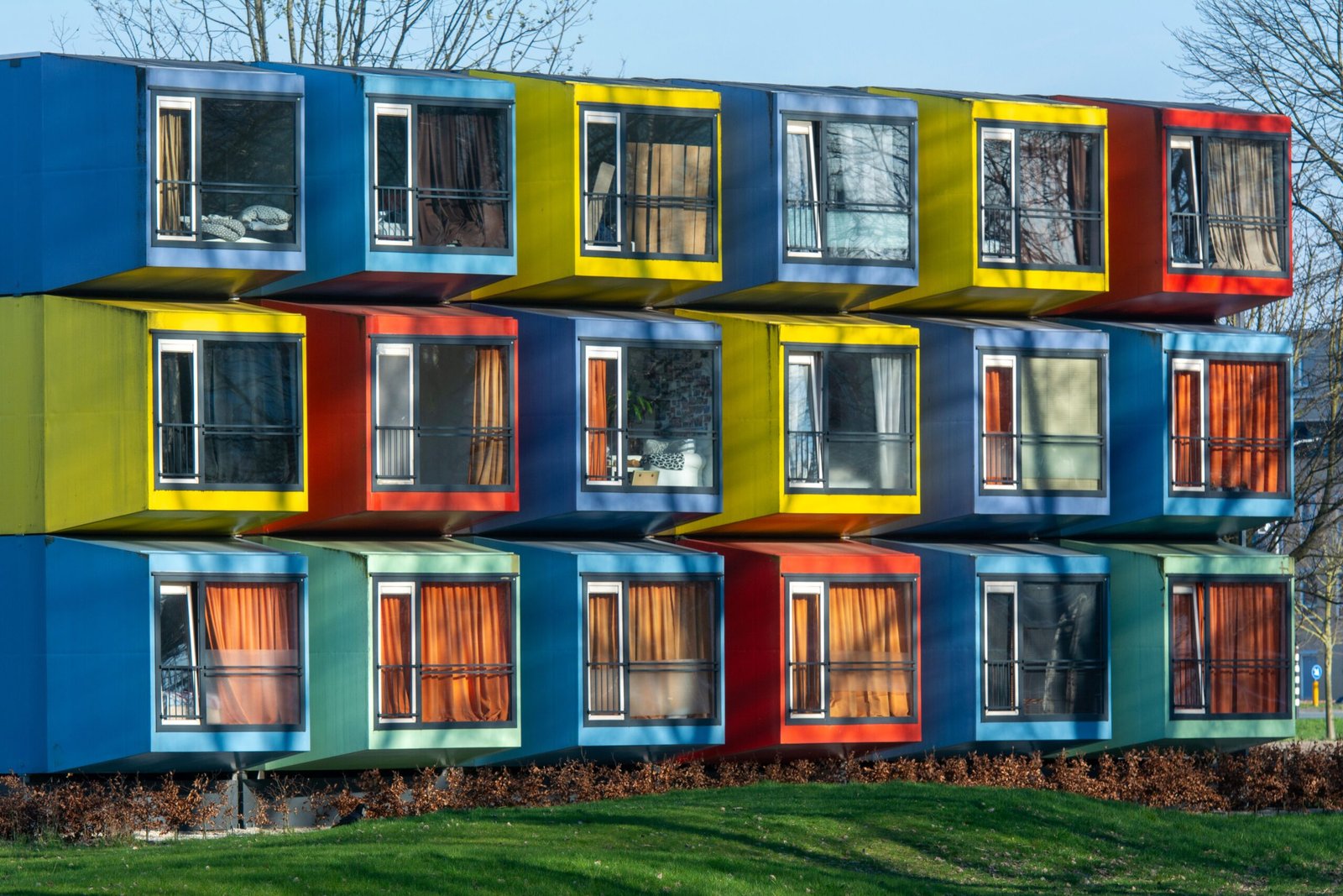 Vibrant exterior of colorful modular housing units with varied window designs.