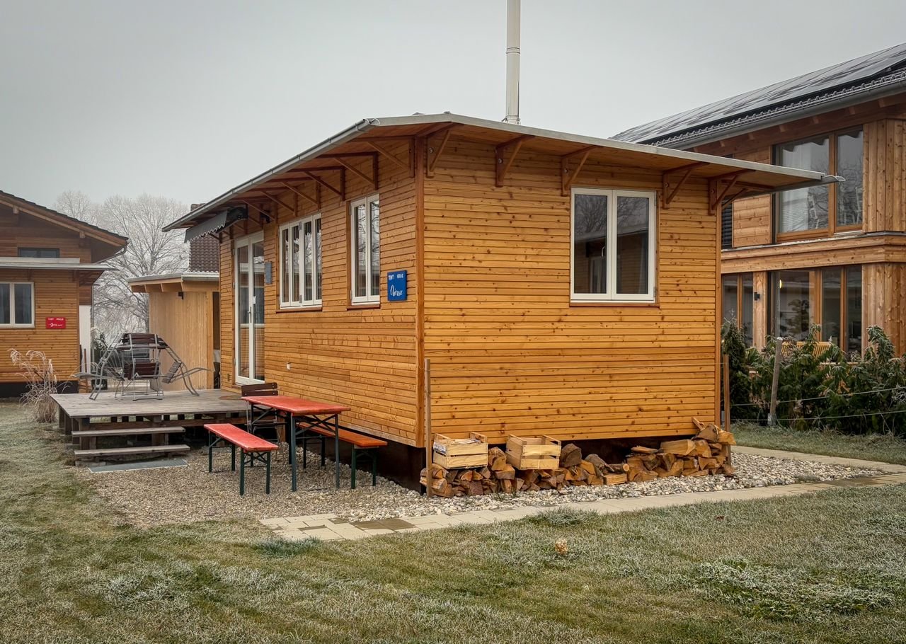 A charming wooden cabin with a small porch in a peaceful countryside location.
